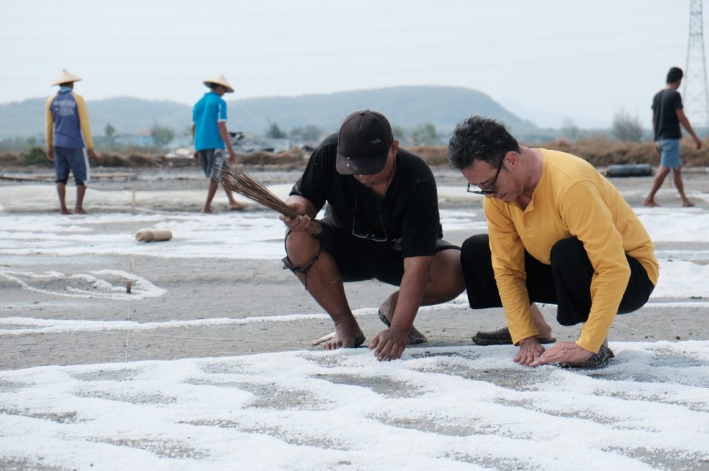 Eggy Yunaedi seorang perupa dan pegiat budaya bersama petani garam Dasun sedang melukis tambak dengan garam di kawasan situs Tambak Gede Desa Dasun Kecamatan Lasem