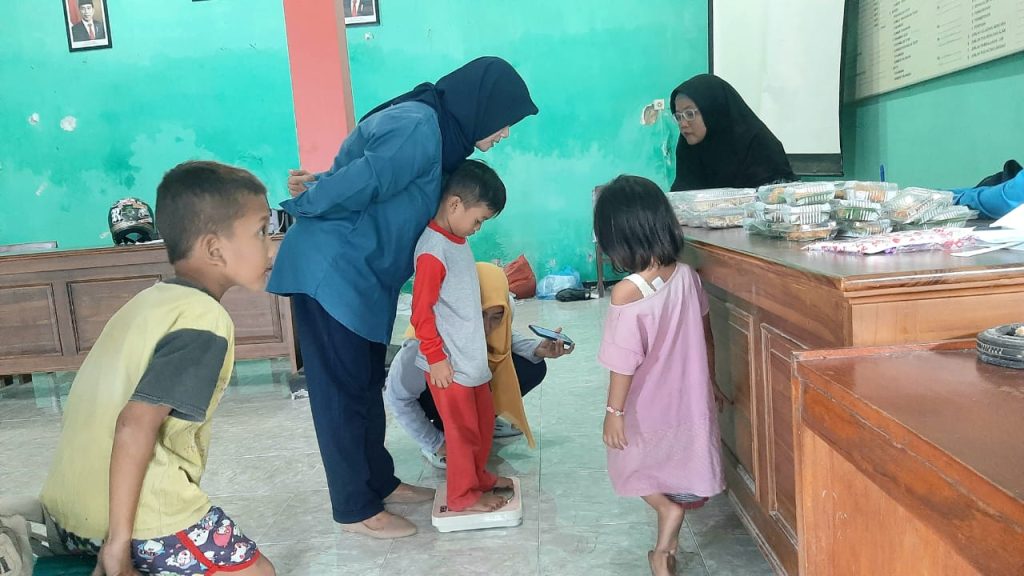 Sesi pengukuran berat badan balita yang menjadi sasaran intervensi gizi Dinas Kesehatan Rembang di balai Desa Sumberjo